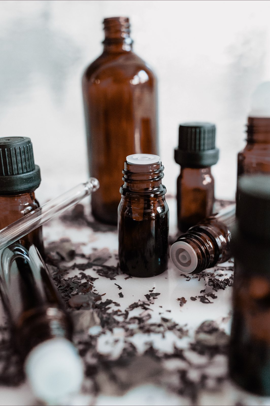 Amber dropper bottles on a white table with dried lavender scattered around them