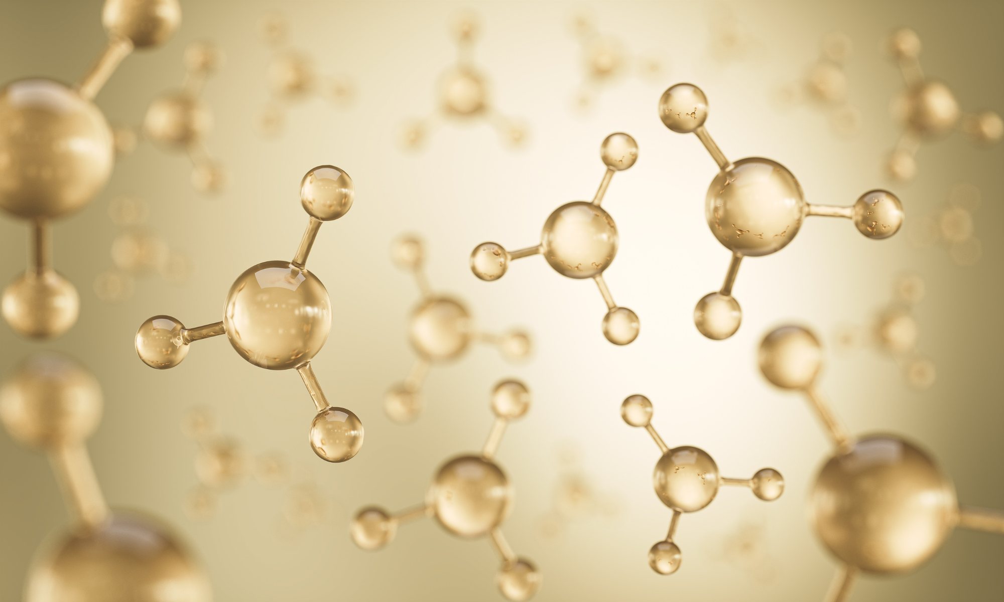 Gold molecule models floating on a warm cream background